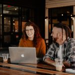 Two professionals work together in a coffee shop.