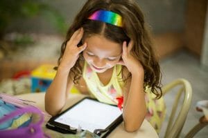 young girl leaning over a tablet